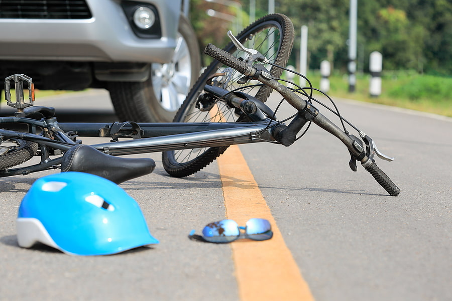 Image of a bicycle and helmet on the ground in front of a car after a California bicycle accident.