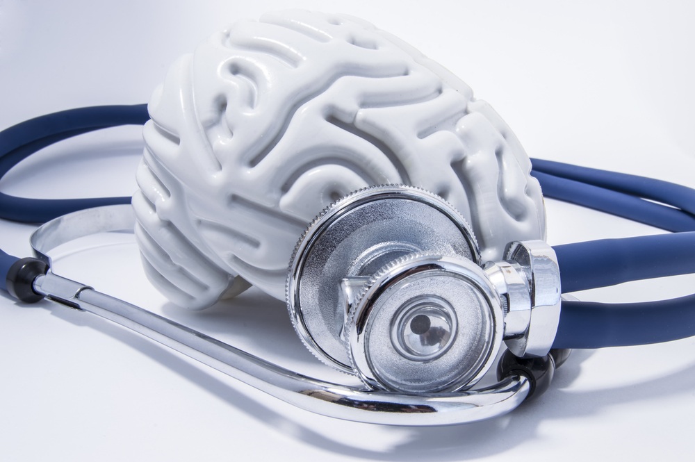 Stethoscope placed against a white model of a human brain, symbolizing medical evaluation and diagnosis of traumatic brain injury.