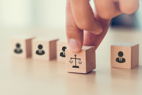 Hand selecting a block with justice scales, representing wage and hour lawyers