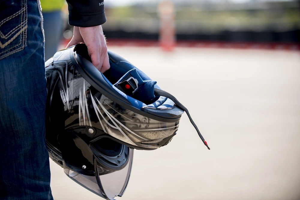 Closeup of a biker holding a motorcycle helmet in his hand.