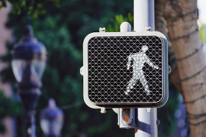 A white pedestrian crossing sign at a crosswalk